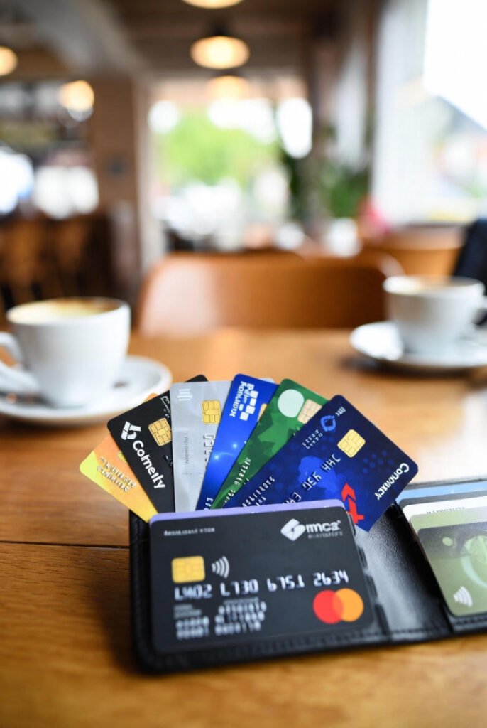 a wallet with multiple business credit cards fanned out on a wooden café table.